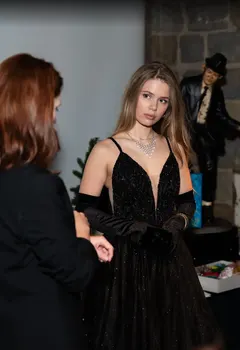 Black glitter evening gown with plunging neckline and crystal necklace from Velvet Dress Vienna at an event