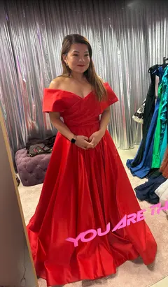 Client in a red off-the-shoulder satin ball gown at a fitting in the Velvet Dress Vienna showroom